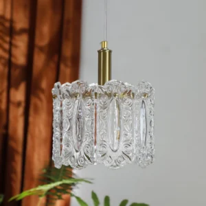 Kalmar pendant lamp illuminated above table with warm glow casting soft light through embossed glass