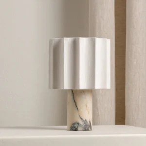 Kane rechargeable table lamp positioned on side table near linen curtains, three-quarter angle showing veined marble base and light fabric shade