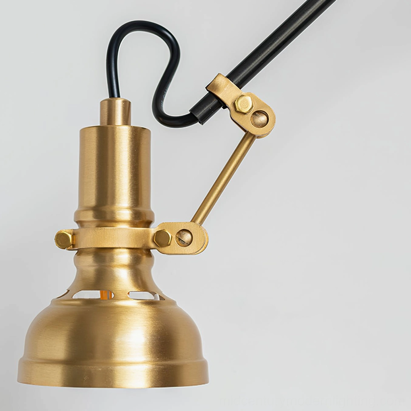 Close-up detail of Kane wall lamp's articulating brass pivot joints and adjustable knuckle mechanism with brushed brass finish