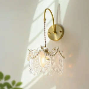 Illuminated Kano glass wall light with ruffled shade and pearl accents, close-up front view in natural sunlight