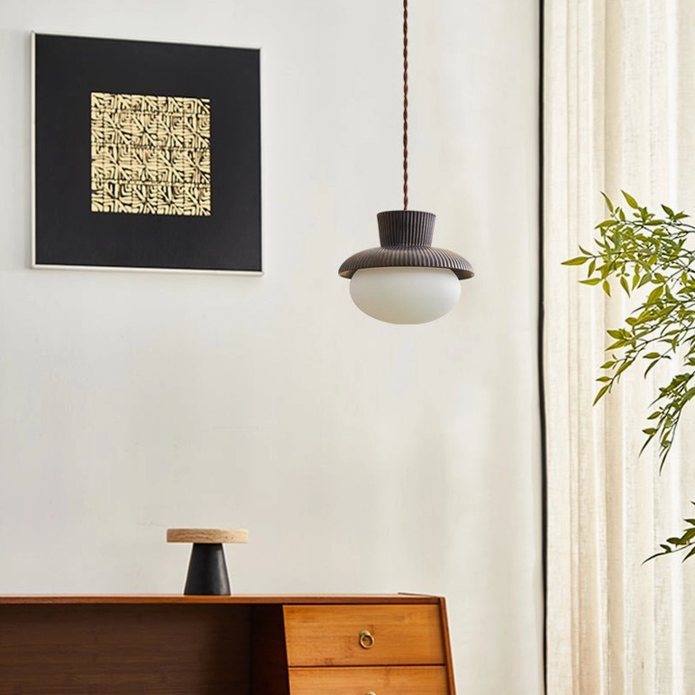 Kaskad mid-century modern pendant light in home space with wooden sideboard and wall art, distant side view showing fixture scale and integration