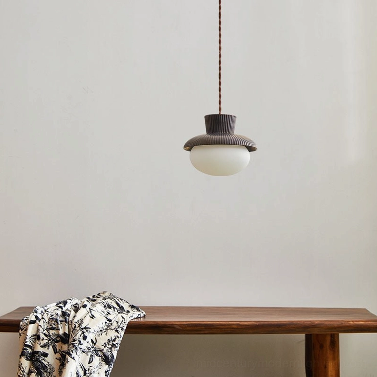 Kaskad ceramic pendant light fixture hanging in home scene with wooden bench and patterned textile, minimalist frosted glass shade aesthetic