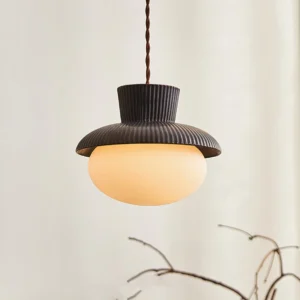 Illuminated Kaskad pendant lamp glowing warm light through frosted glass shade, overhead perspective showing diffused luminosity and interior home setting