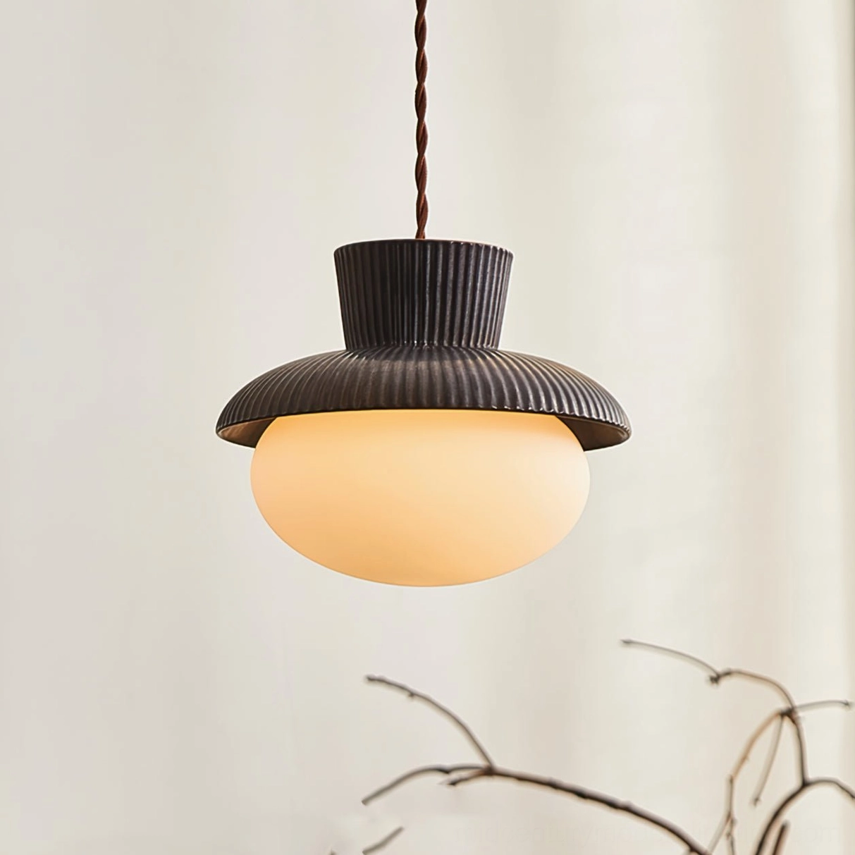 Illuminated Kaskad pendant lamp glowing warm light through frosted glass shade, overhead perspective showing diffused luminosity and interior home setting