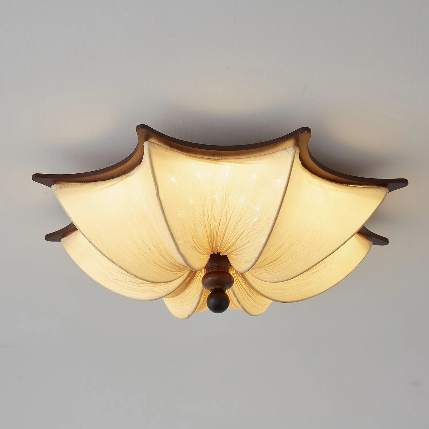 Close-up detail of Kateo ceiling lamp showing intricate hand-pleated textile shade construction and sculptured wood trim