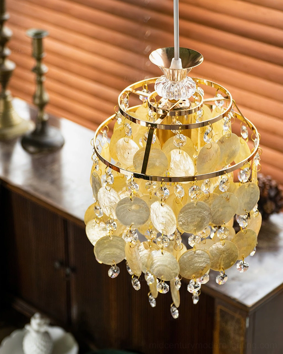 Amber capiz shell Katinka chandelier pendant with gold ring frame and dangling crystals, three-quarter front view vintage sideboard display