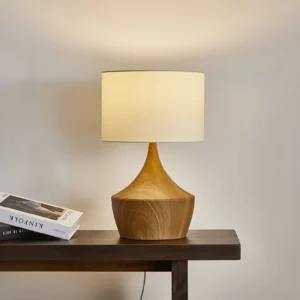 Kendra table lamp lit on console table casting warm ambient light with books and decor