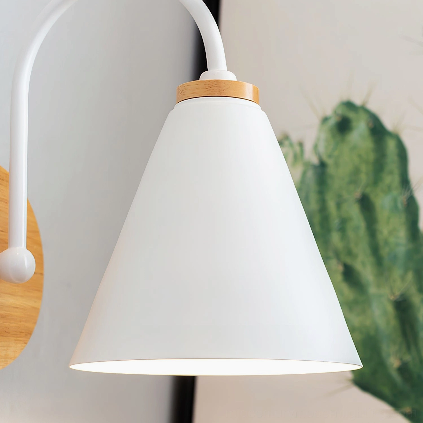 Close-up of Kenji wall lamp shade revealing smooth matte white conical metal design and light diffusion