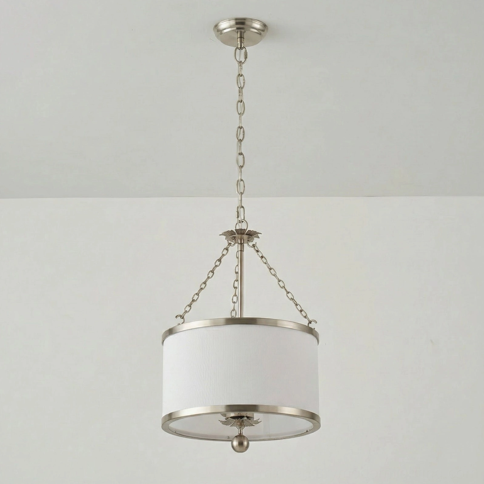 Kian pendant light with silver metallic hardware and white fabric drum shade, studio photograph