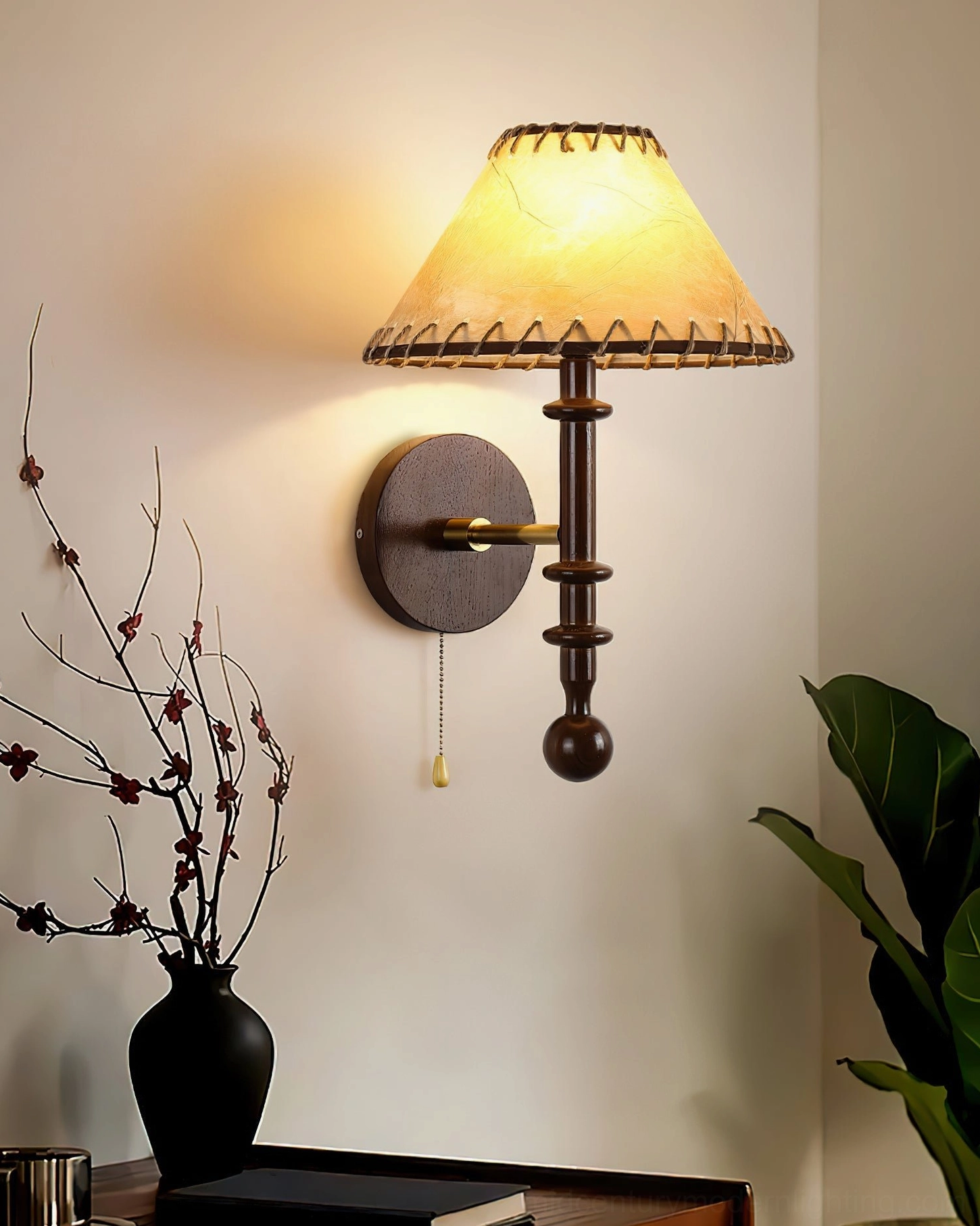 Black Kibo wood wall lamp installed above bedroom side table with vintage decor and dried floral arrangements