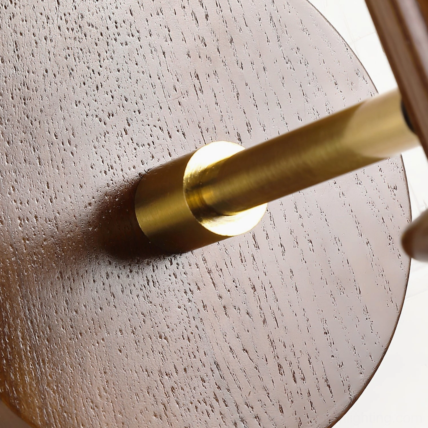 Close-up detail of Kibo wall sconce hardware showing brass gold metal rod and textured round wall mounting plate