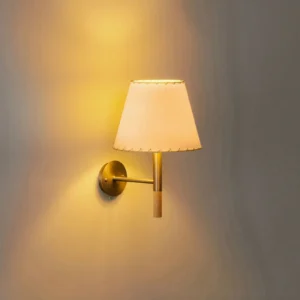 Kilkee wall sconce mounted on interior wall with warm brass nickel finish and glowing ambient light