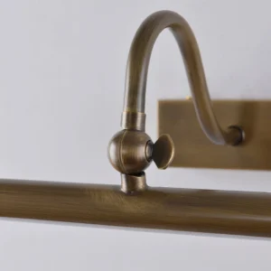 Close-up detail of brushed antique brass cylindrical form and LED module, overhead angle showing sconce construction