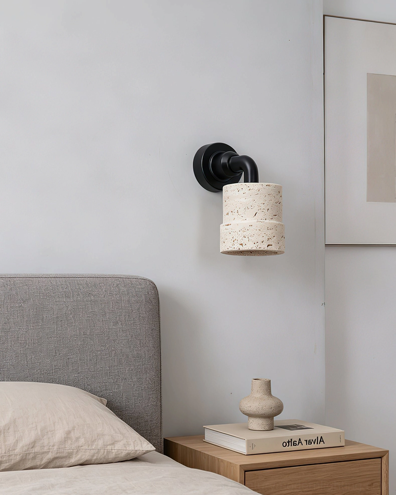 Kiran tiered travertine wall light in minimalist bedroom providing warm wabi-sabi illumination above nightstand