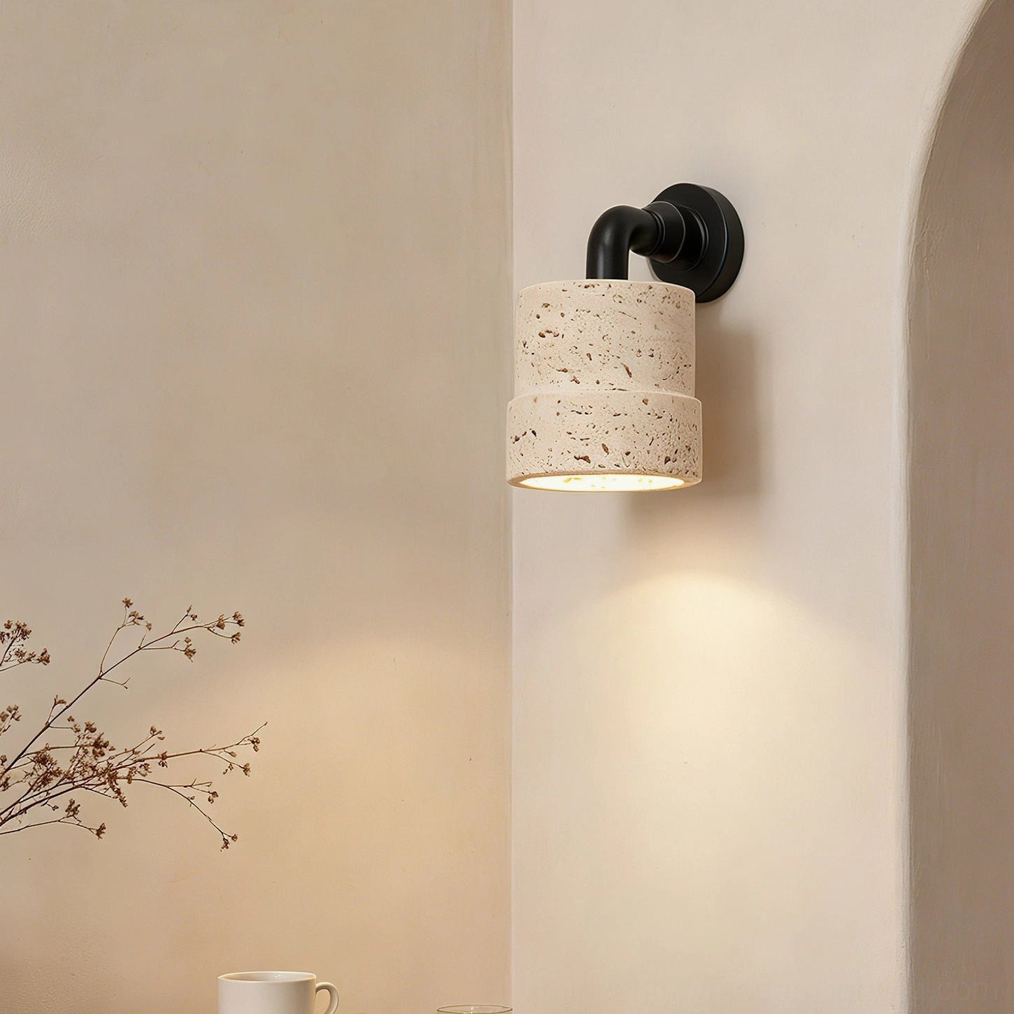 Kiran tiered travertine wall sconce with two-tier stone shade in minimalist interior with archway