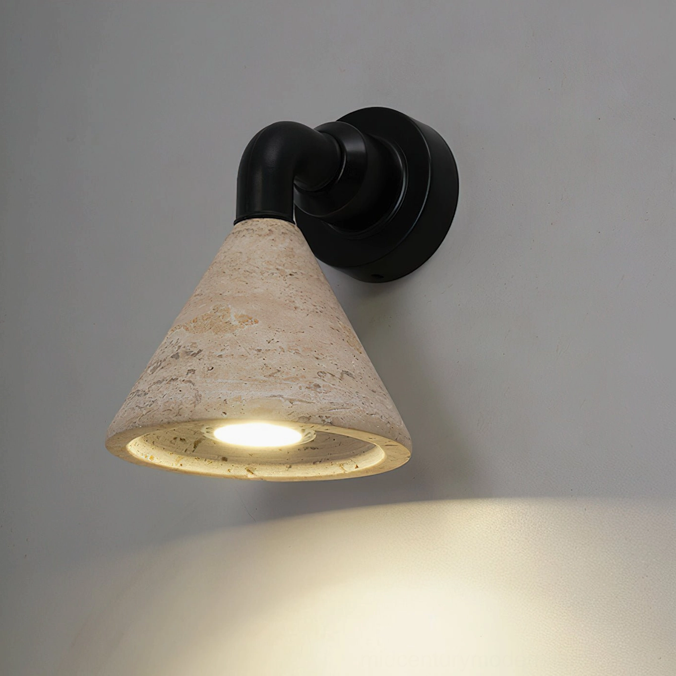 Kiran travertine wall sconce glowing with warm LED light in gallery-style minimalist interior
