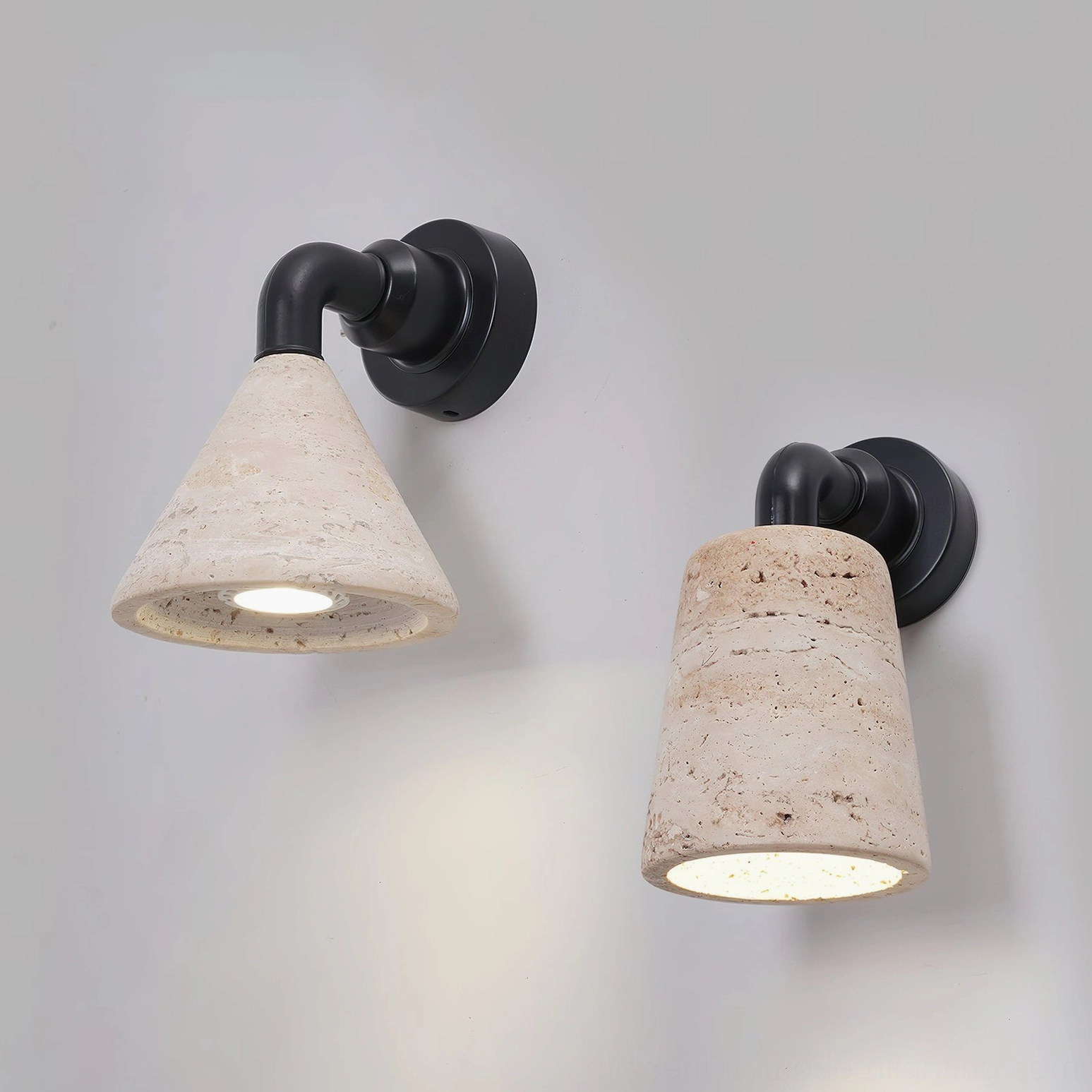 Two Kiran travertine wall light variants with different stone shade shapes photographed overhead on white background