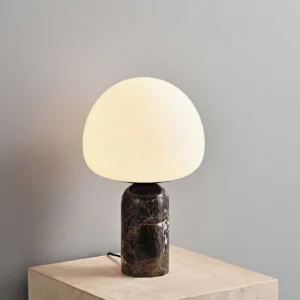 Lit Kizu table lamp emitting warm ambient light, three-quarter view on light stone table