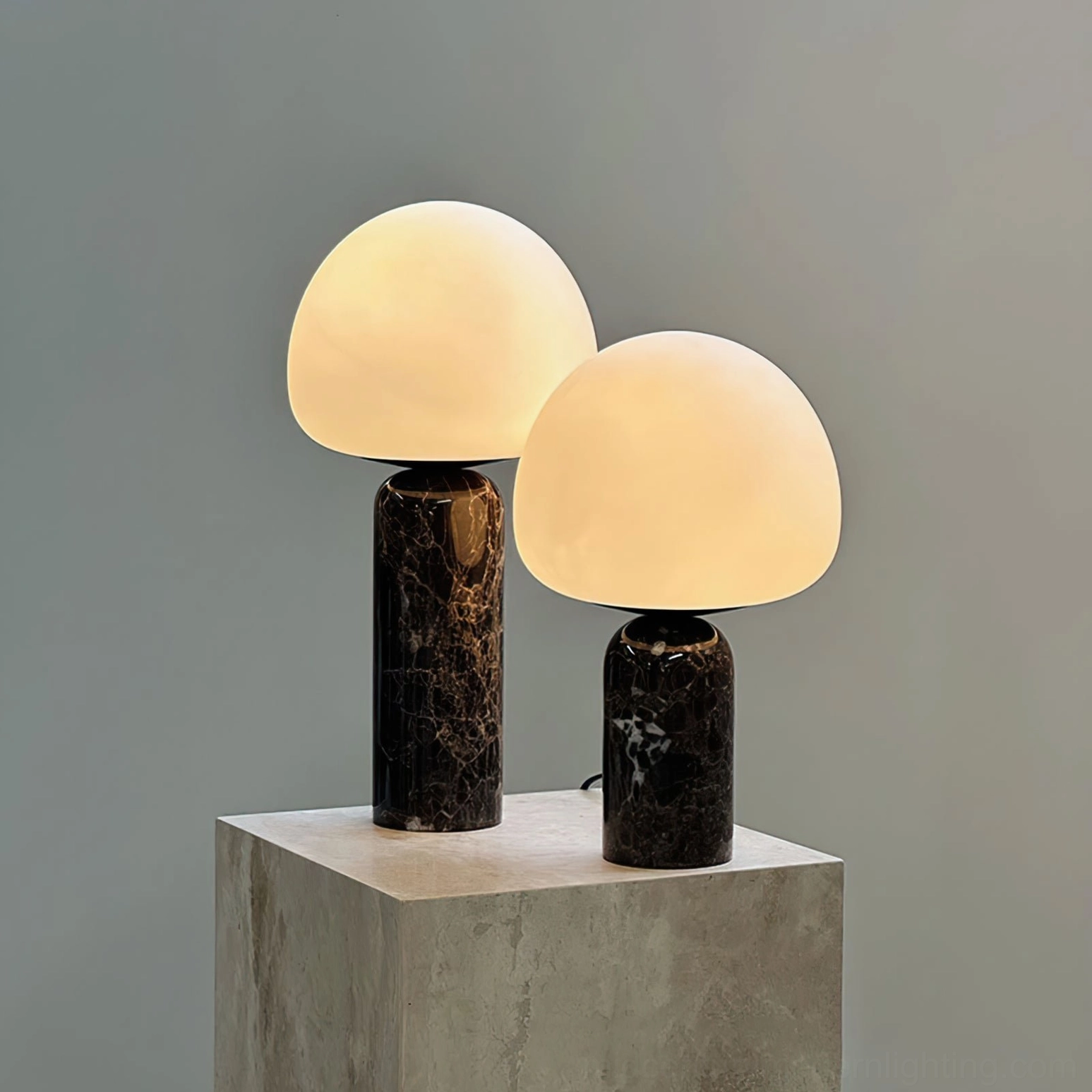 Two Kizu table lamps with warm illumination on concrete stone table, different marble base heights
