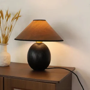 Kodu lamp creating warm ambient light on wooden bedroom nightstand with dried flower decor and wabi-sabi styling