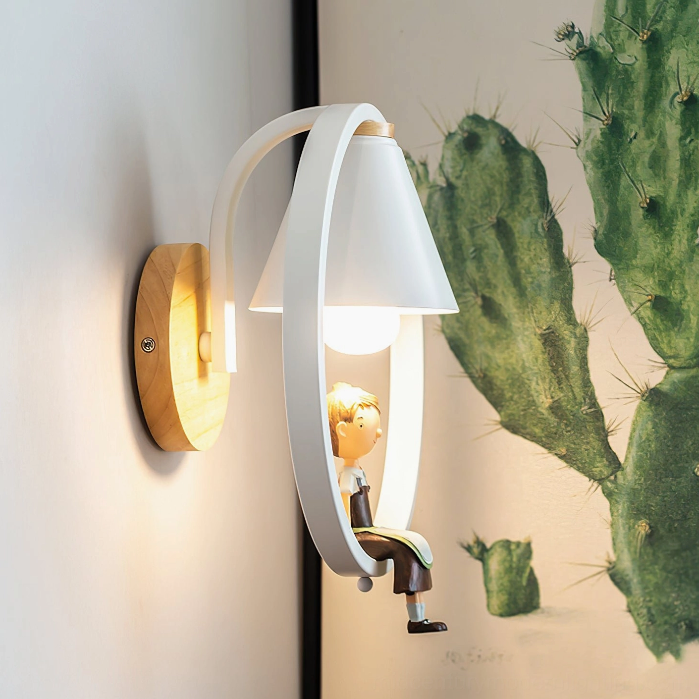 Kona boy-themed wall sconce mounted on indoor wall with cactus wall art, side angle view showing wood grain base and white frame