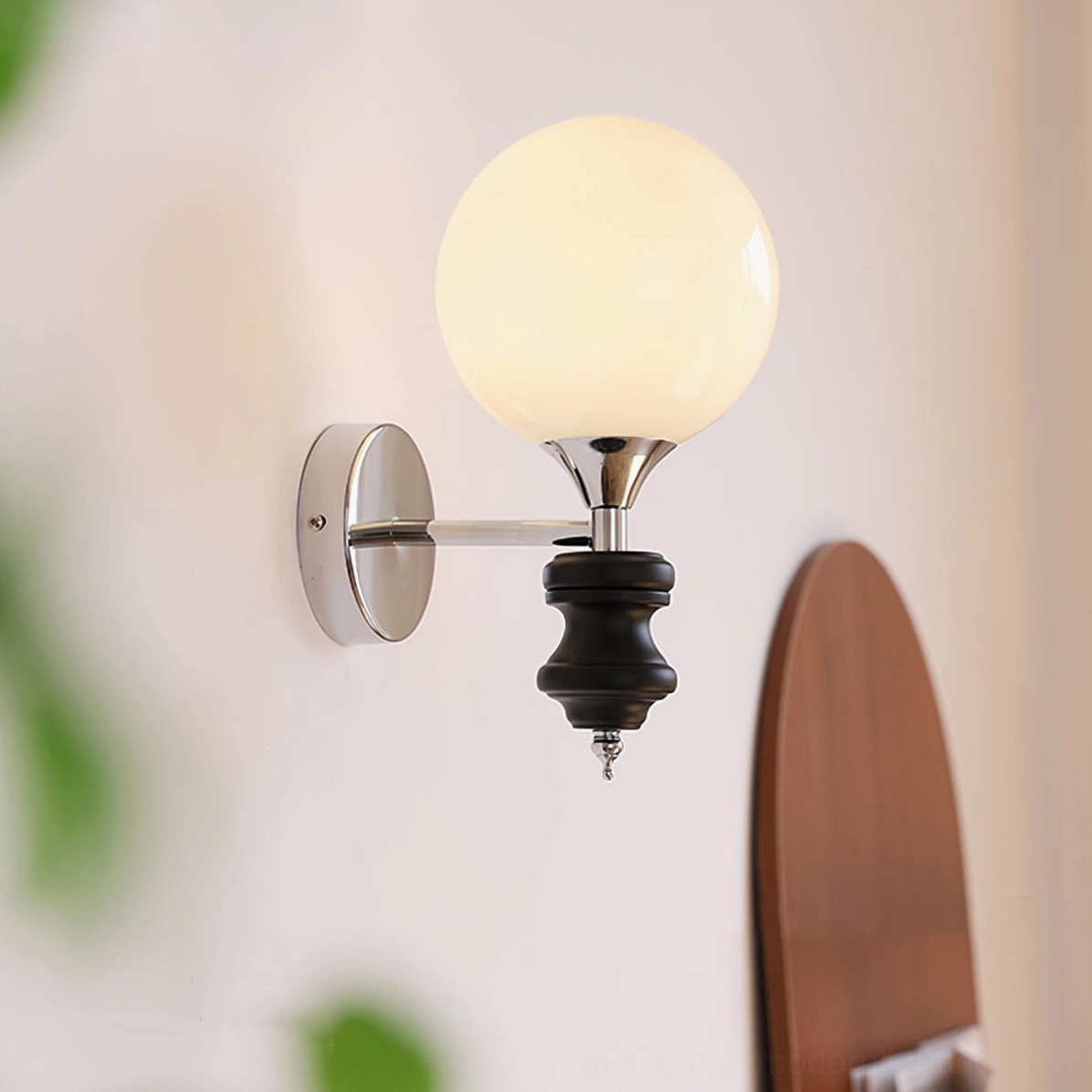 Koscina wall lamp illuminated in residential entryway - warm ambient light casting glow from chrome fixtures and frosted glass