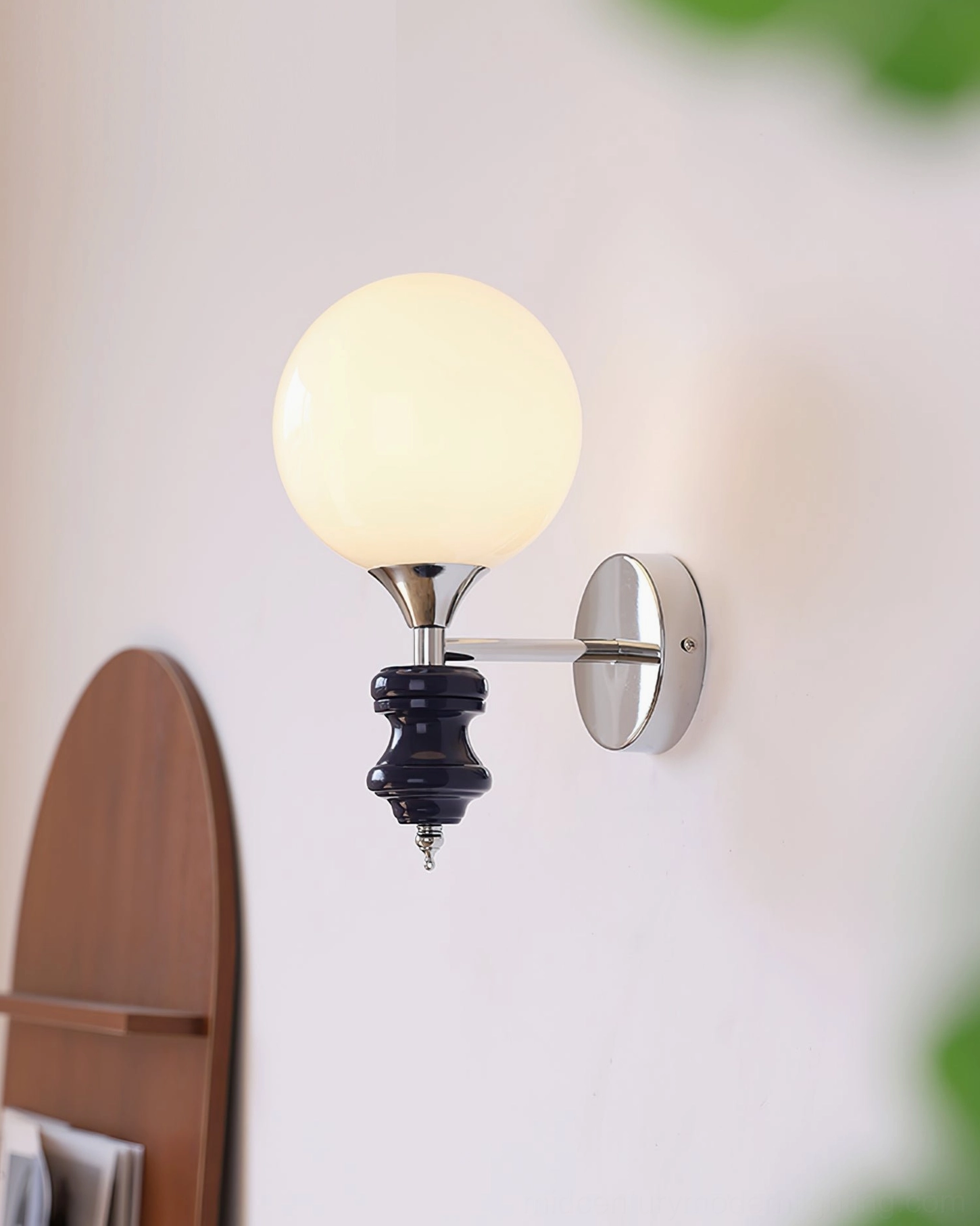 Koscina wall lamp three-quarter angle view - sculptural form showing chrome hardware and frosted glass sphere integration