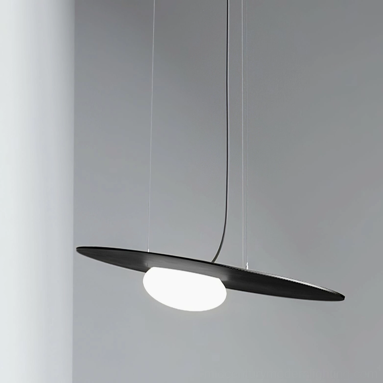 Matte black Kwic pendant lamp shown at eye level with suspension wire against gray background, modern minimalist design