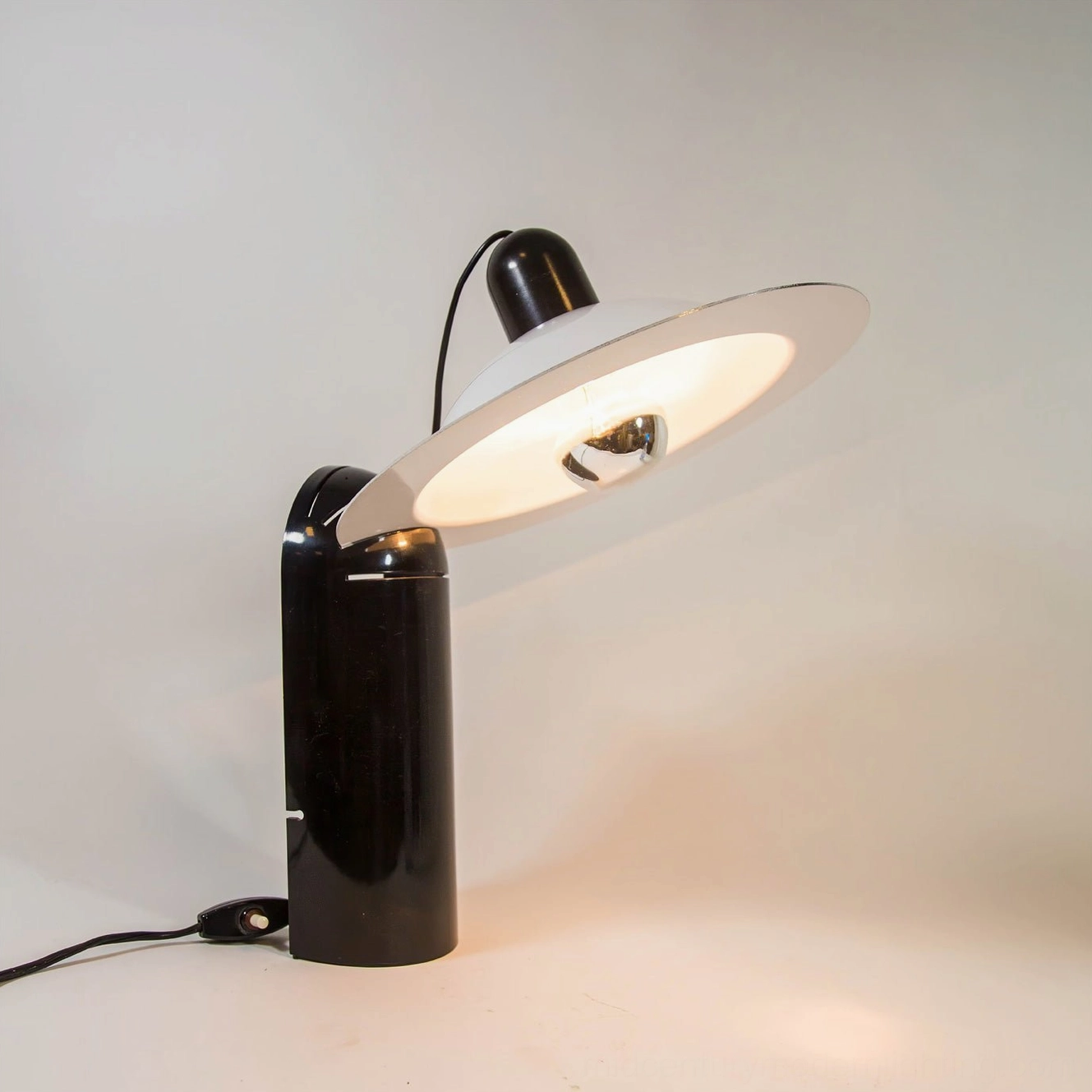 Lampiatta table lamp demonstrating adaptive light direction capability with adjustable disc shade and minimalist aesthetic