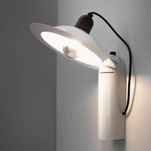 Lampiatta wall lamp mounted in indoor corner view, featuring adjustable shade mechanism and modern sculptural design from low front angle