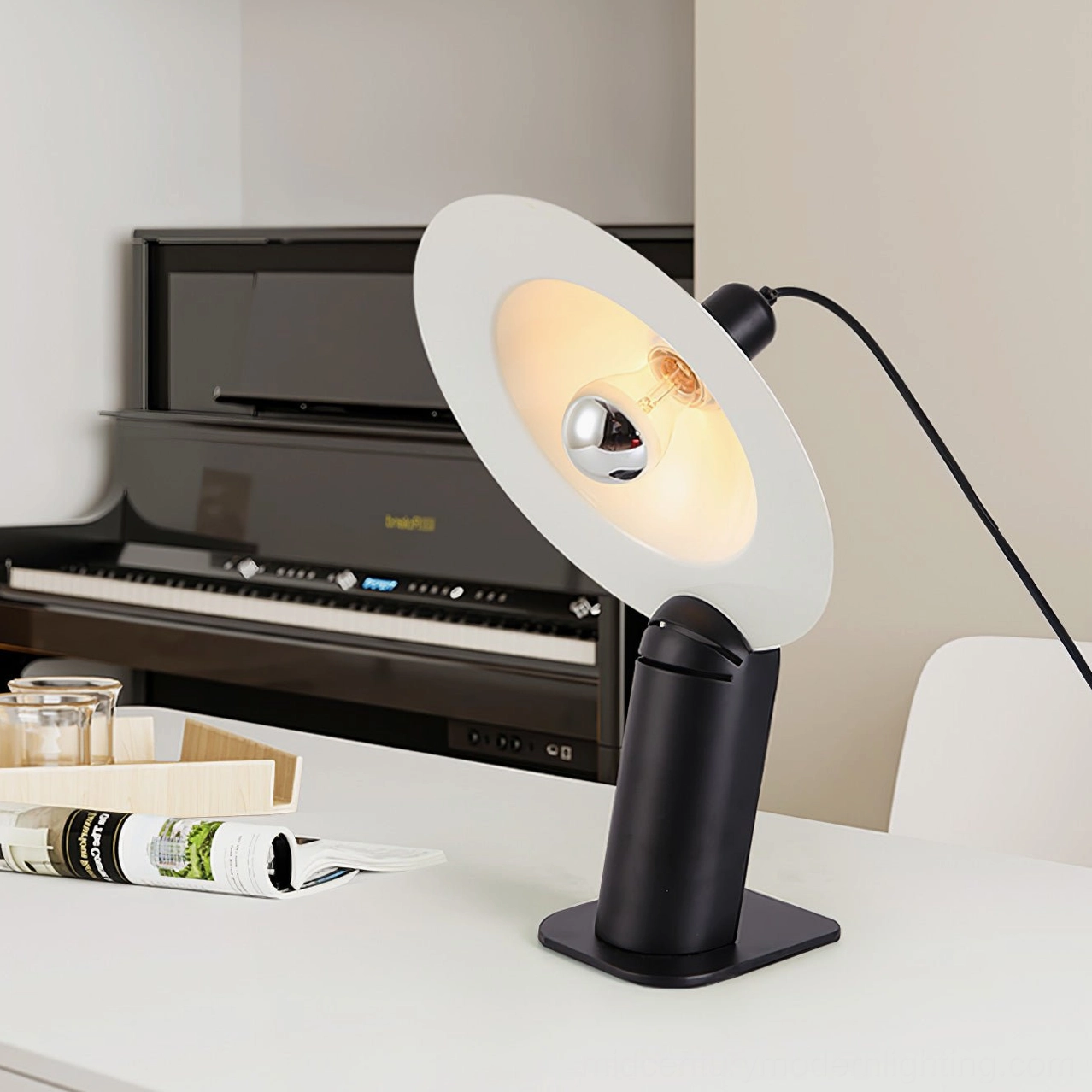 Matte black Lampiatta disc lamp positioned on piano desk with architectural lighting design and clean lines