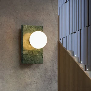 Green marble wall sconce installed in residential stairwell showing natural stone texture and warm ambient lighting