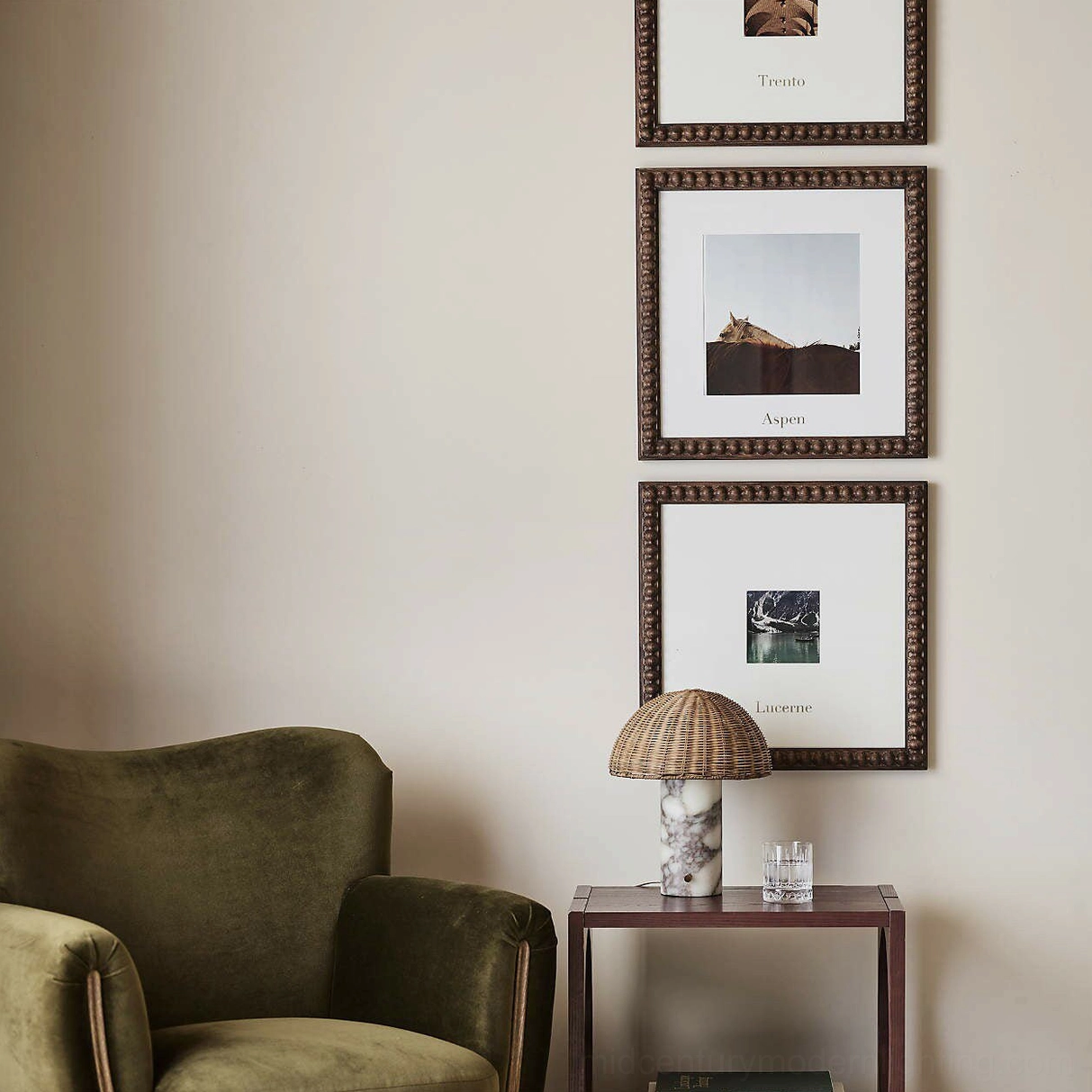 Compact rattan and marble table lamp on cozy living room side table with velvet armchair and wall art