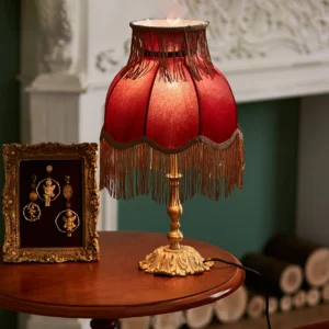 Lanna red tassel table lamp styled on vintage fireplace side table with ornate brass base and decorative framed artwork