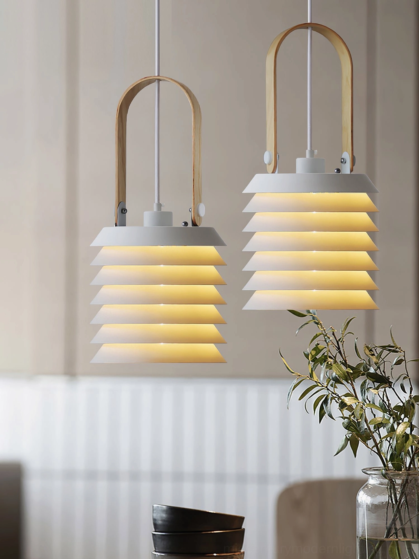Minimalist lantern pendant lights above dining counter with decorative plant, eye-level view