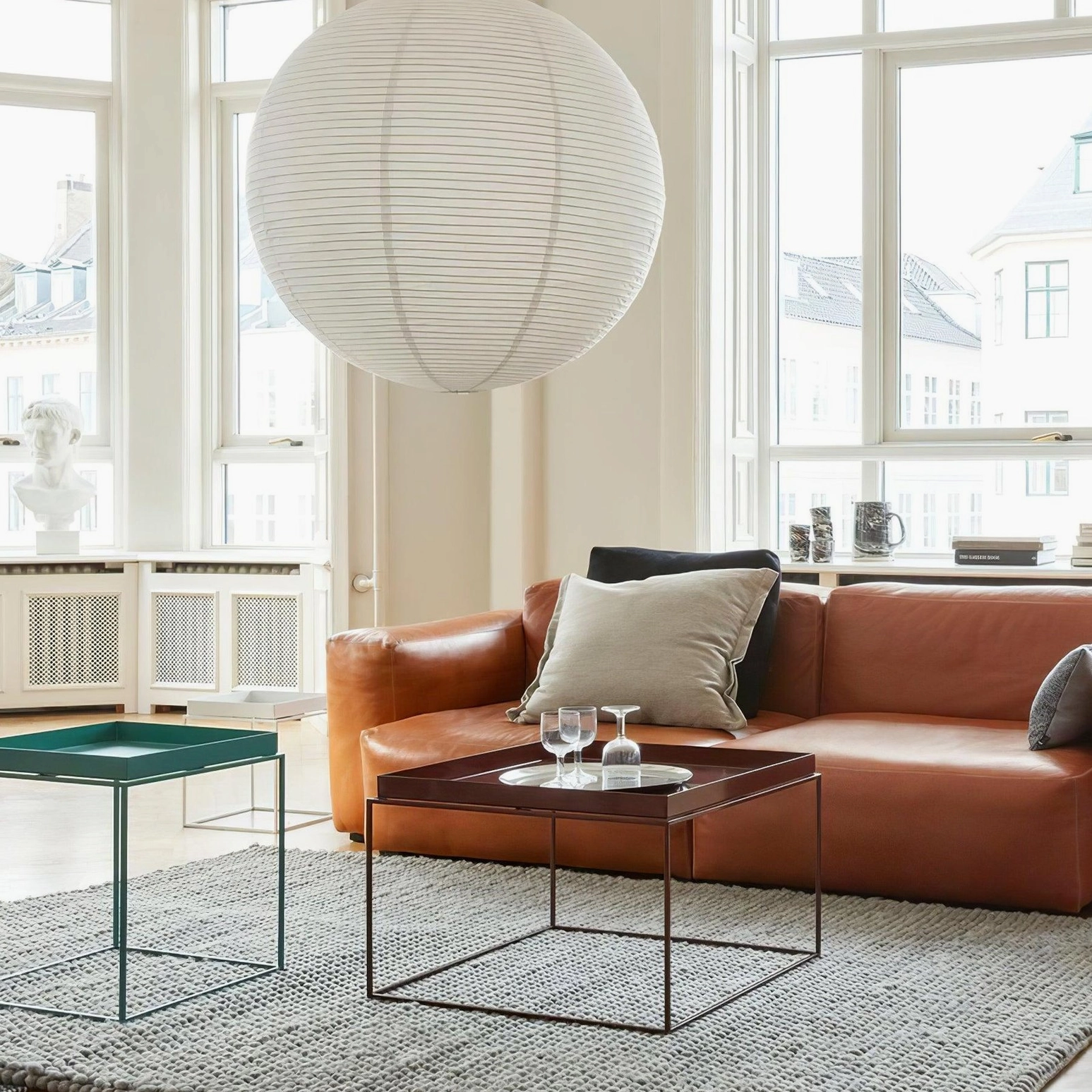 Large white washi paper sphere pendant lamp in bright Nordic style living room with leather sofa, minimalist warm lighting