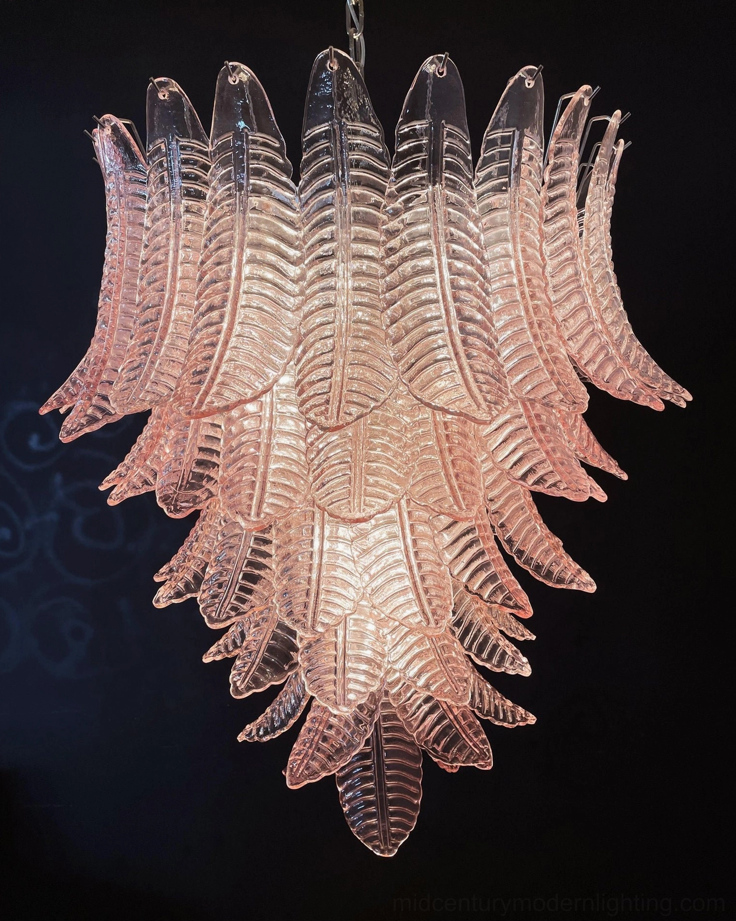 Layered translucent pink glass leaves Murano chandelier low frontal view against scroll pattern backdrop