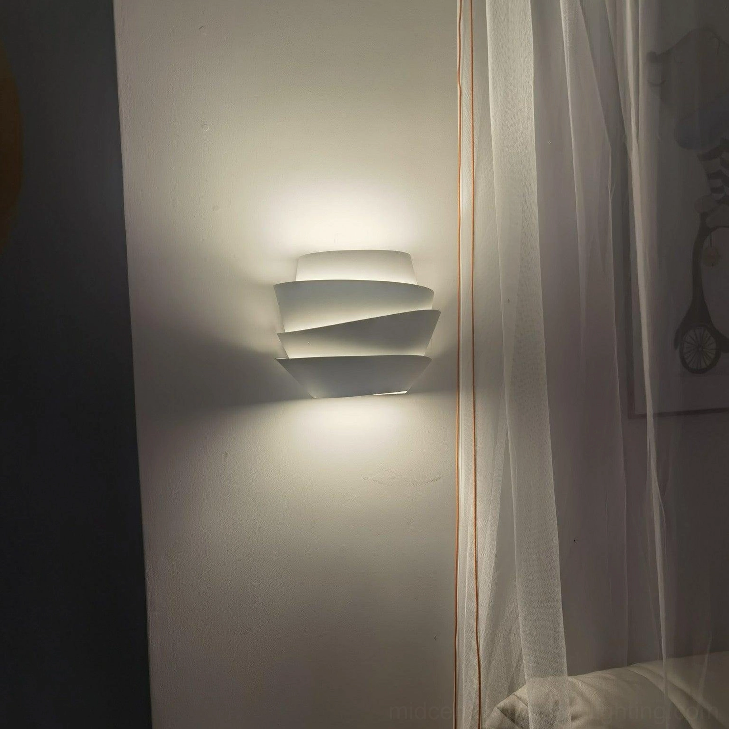 Le Soleil sculptural wall lamp in bedroom setting with sheer curtain and warm ambient glow