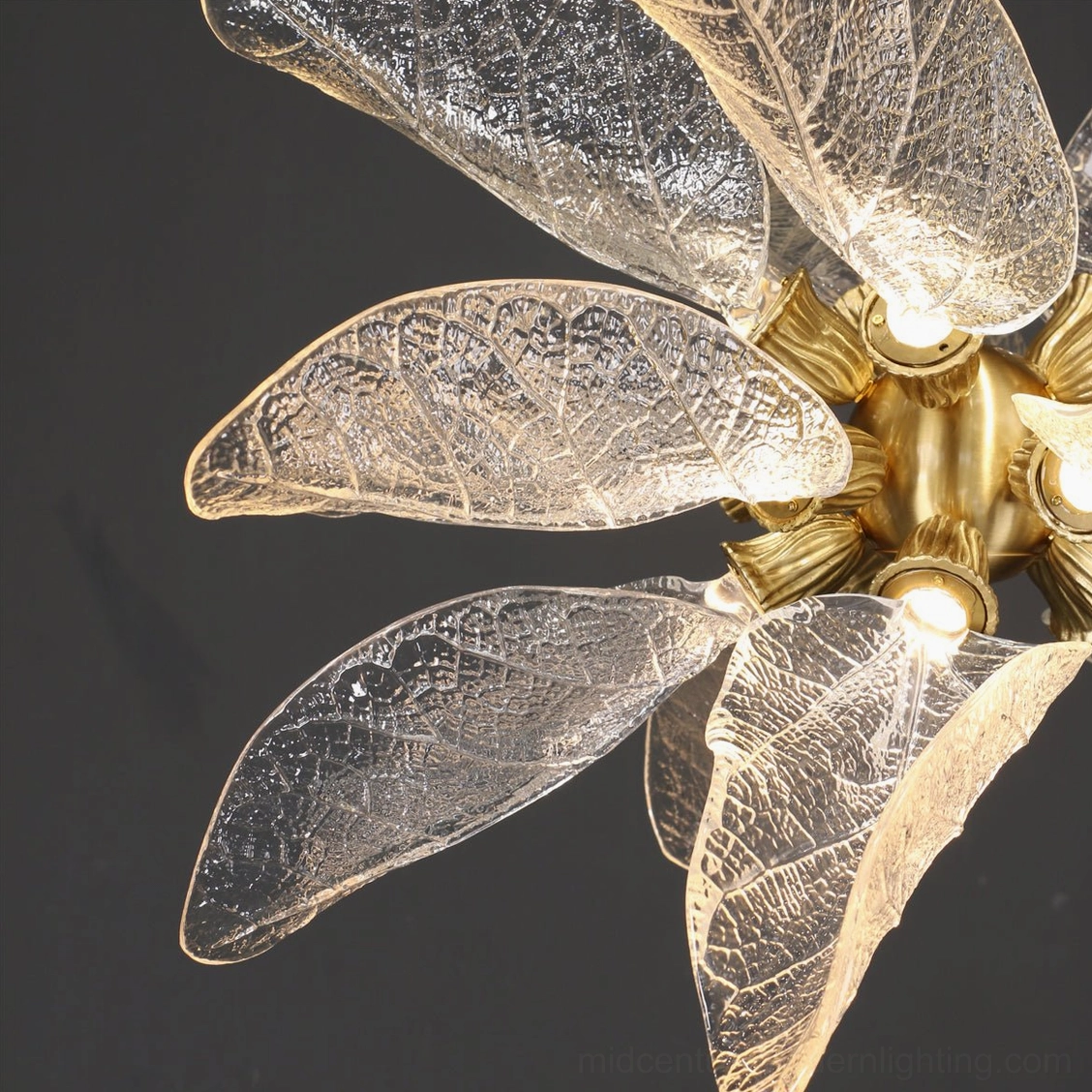Close-up detail of transparent textured glass leaves and brass bulb sockets on chandelier