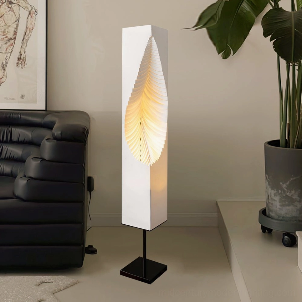 Leaf Floor Lamp in modern living room corner, three-quarter view next to leather sofa and green potted plant
