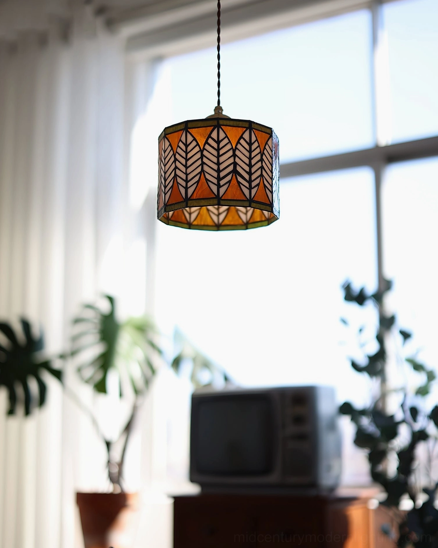 Vintage leaf pattern Tiffany pendant lamp hanging in retro living room with wooden furniture and window