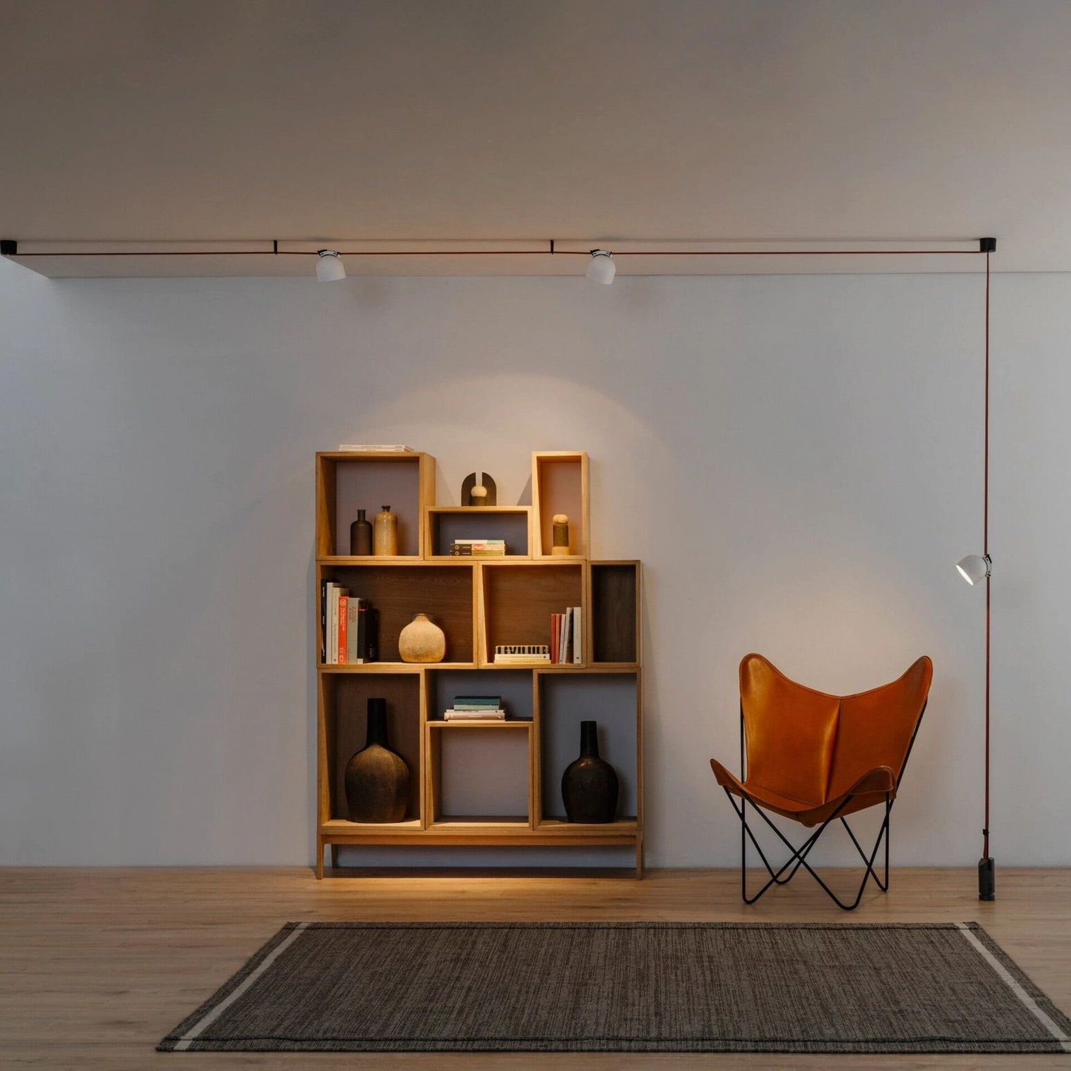 Leather cord pendant lamp fixture in contemporary study room with wooden bookshelf and tan accent chair