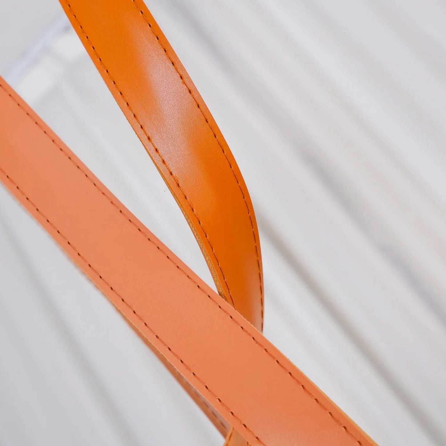 Close-up detail of stitched orange leather strap for sling pendant lamp showing craftsmanship
