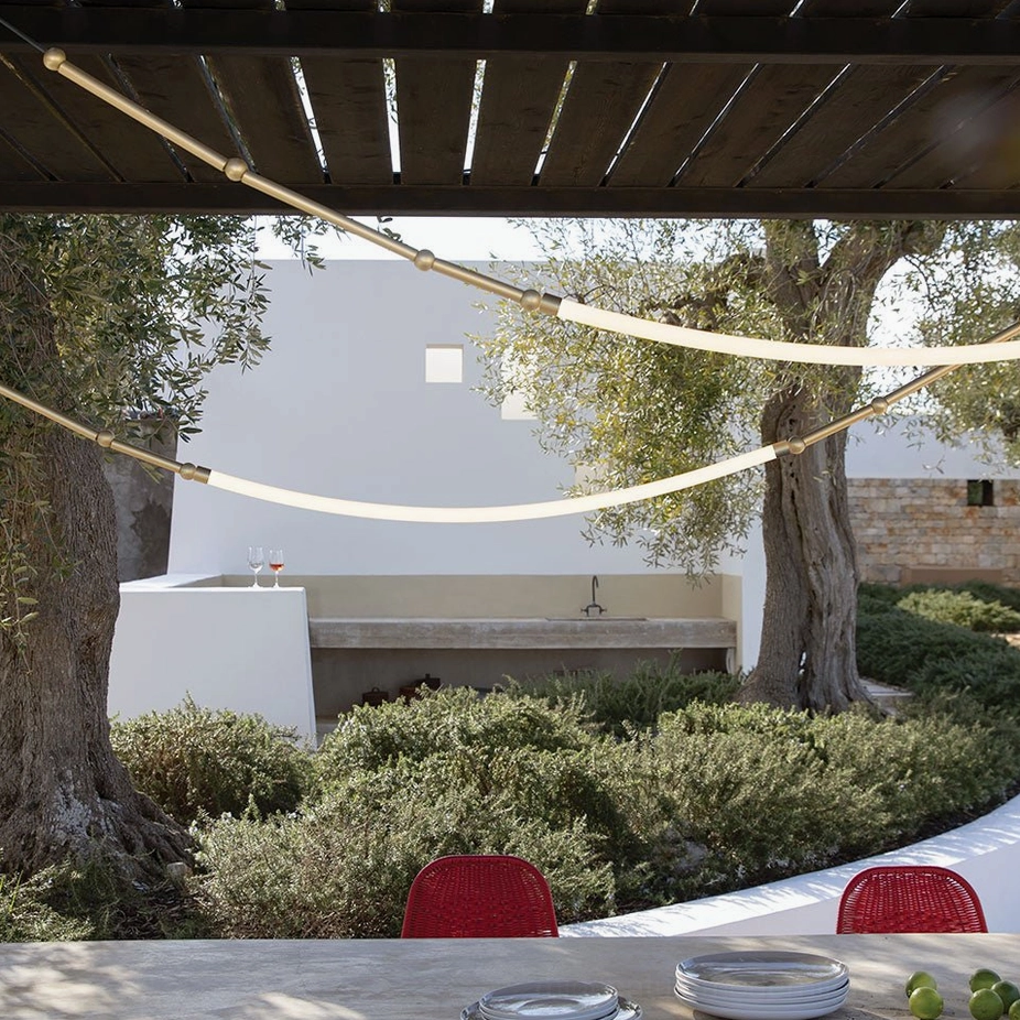 Dual curved Leda LED hanging lamps suspended on outdoor terrace dining area with minimalist natural lighting