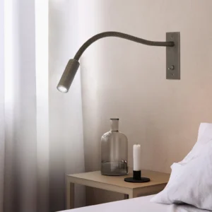Modern LED gooseneck wall sconce mounted bedside, dark grey metal finish at eye level in bedroom