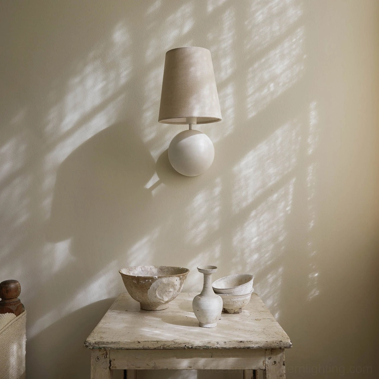 Close-up of Leoda wall sconce showing shadow casting on accent wall, white ceramic sphere and beige shade detail