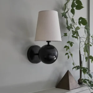Leoda wall sconce mounted in bedroom corner beside green potted plant, neutral farmhouse interior styling