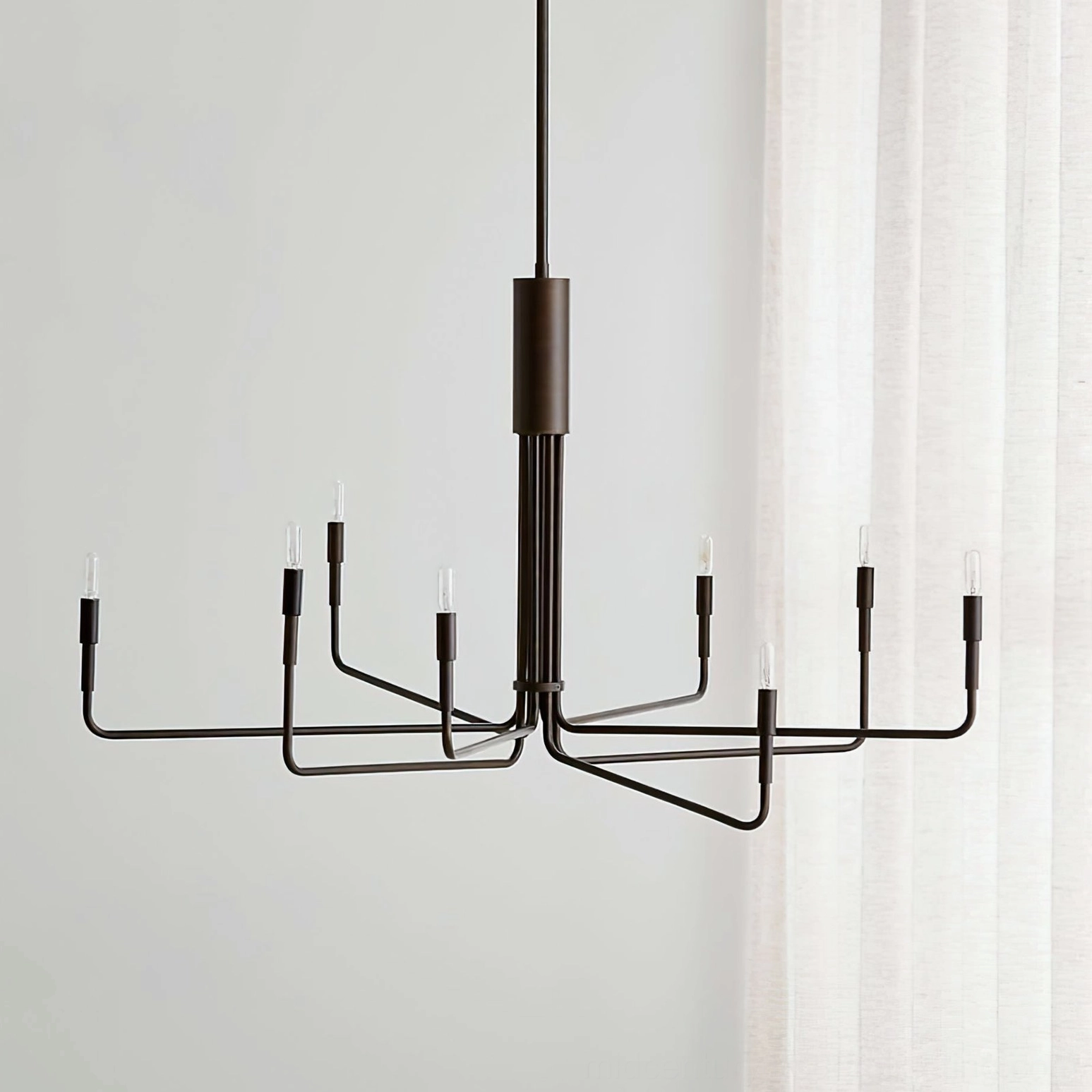 Lepanto 8-light black bronze chandelier angled perspective displaying matte black metal frame with candle-style E14 bulb sockets in modern minimalist interior space