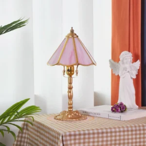 Pink and gold Leslie Tiffany table lamp displayed on home table with angel figurine, book and flower decoration, showing warm vintage ambiance