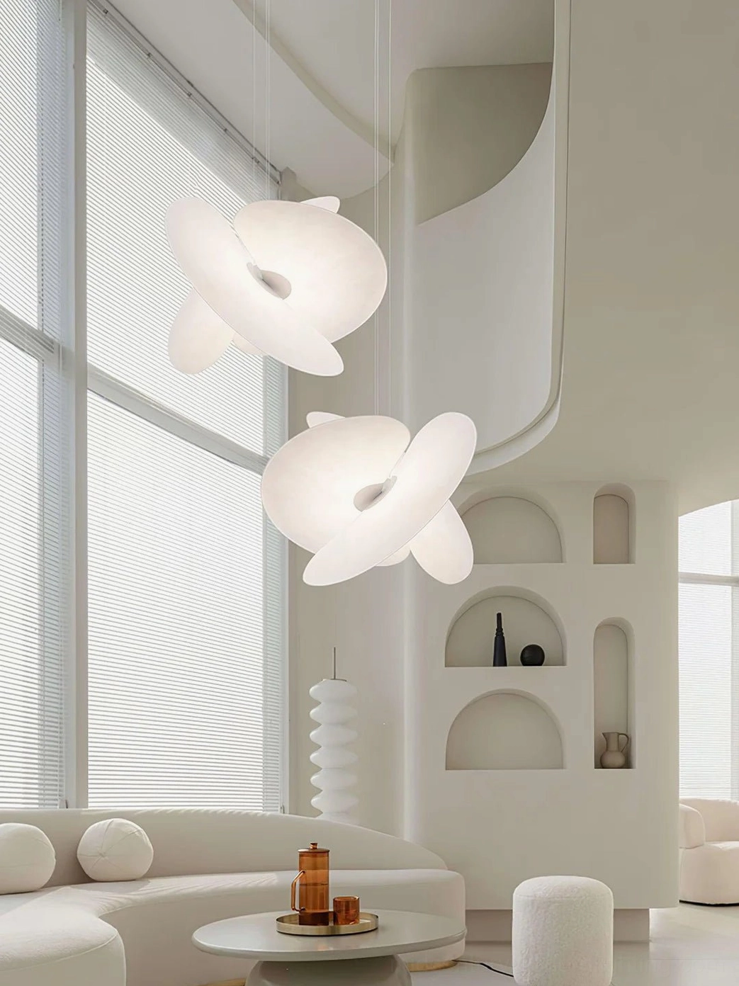 Pair of organic Levante pendant lamps in bright minimalist living room, soft warm glow matching swirling disc design